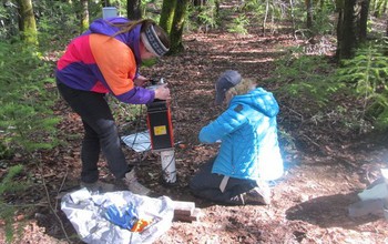 Two female researchers measuring water in bedrock.
